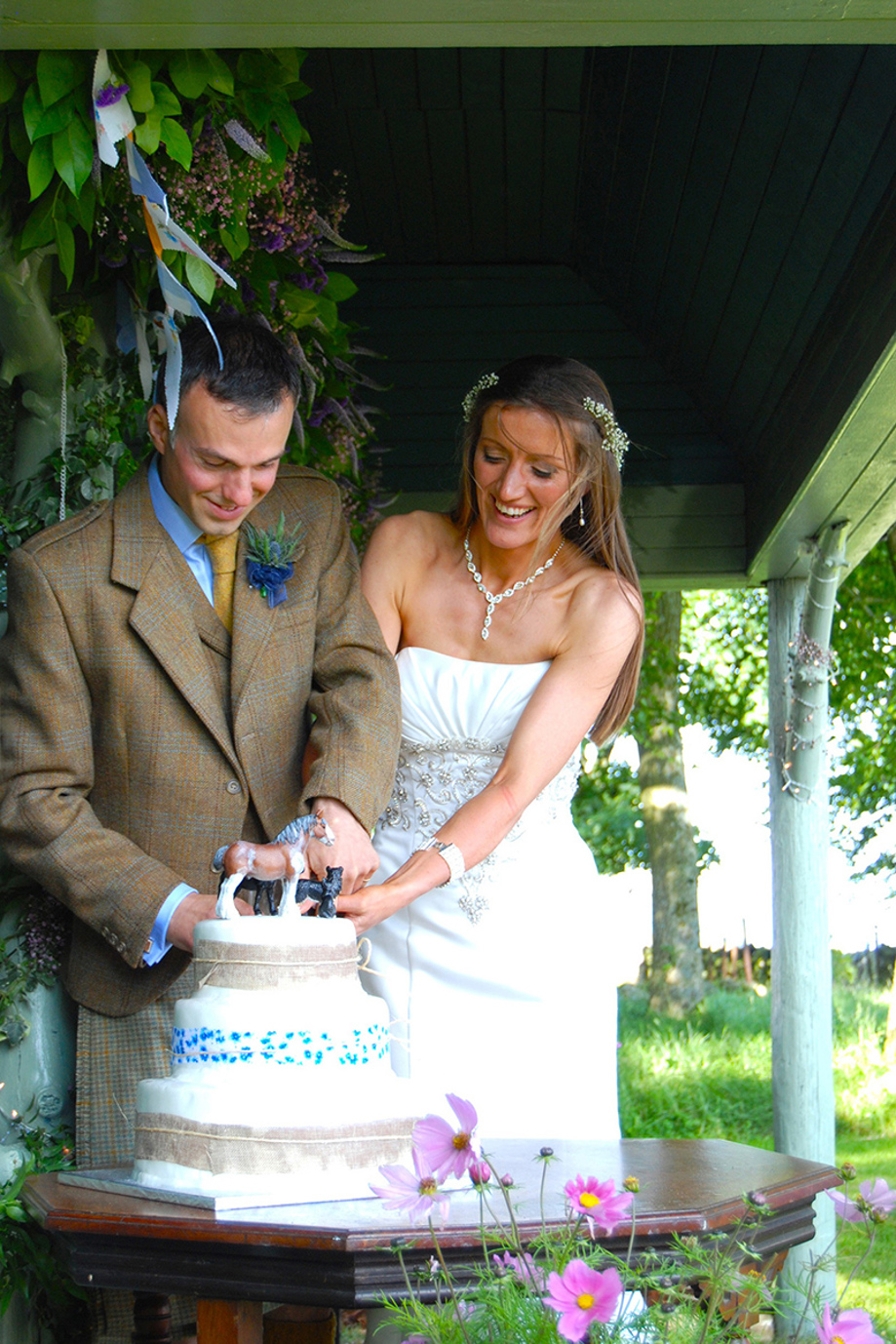 Bride and groom cut tiered wedding cake outside Kinclune